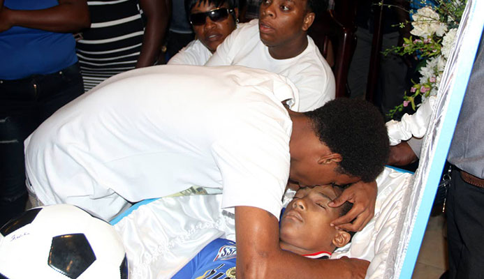 Daniel Simmons hugs his brother of Noah one last time at his funeral yesterday at Gudies Funeral Home in San Fernando. Noah was gunned down on his 16th birthday Tuesday.